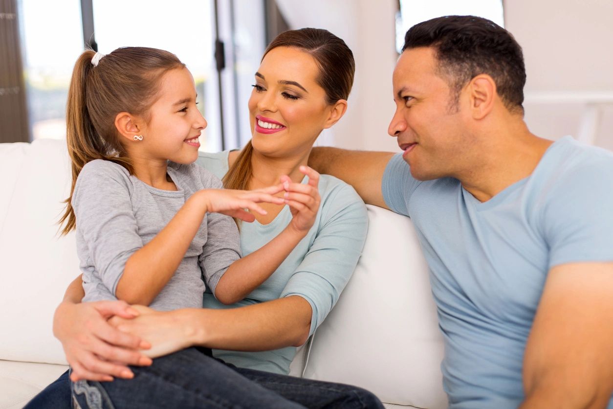 A woman and two men sitting on top of a couch.